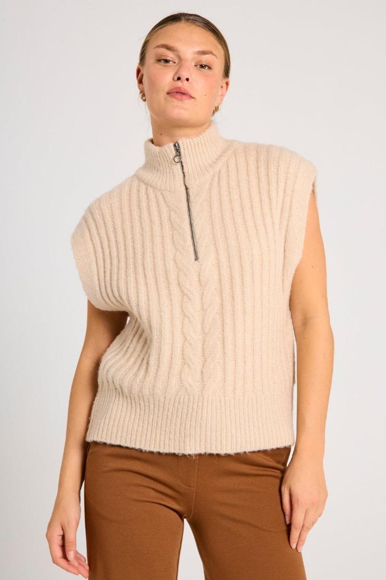 En beige vest med kabelstrikk